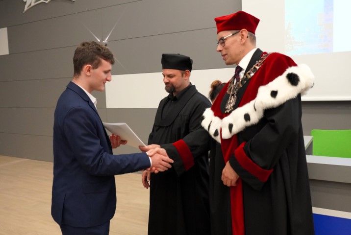 20. Władze uczelni i wydziału wręczają listy gratulacyjne studentom.